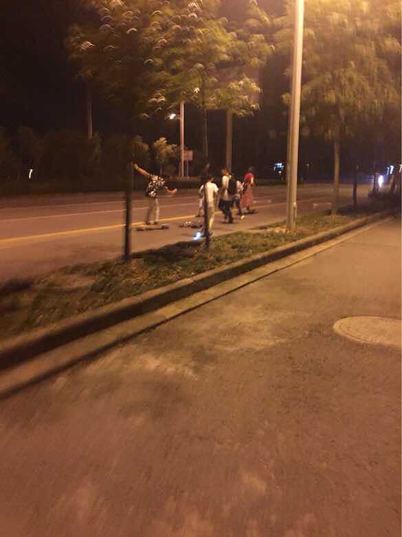 一群學(xué)生在機(jī)動車道玩滑板