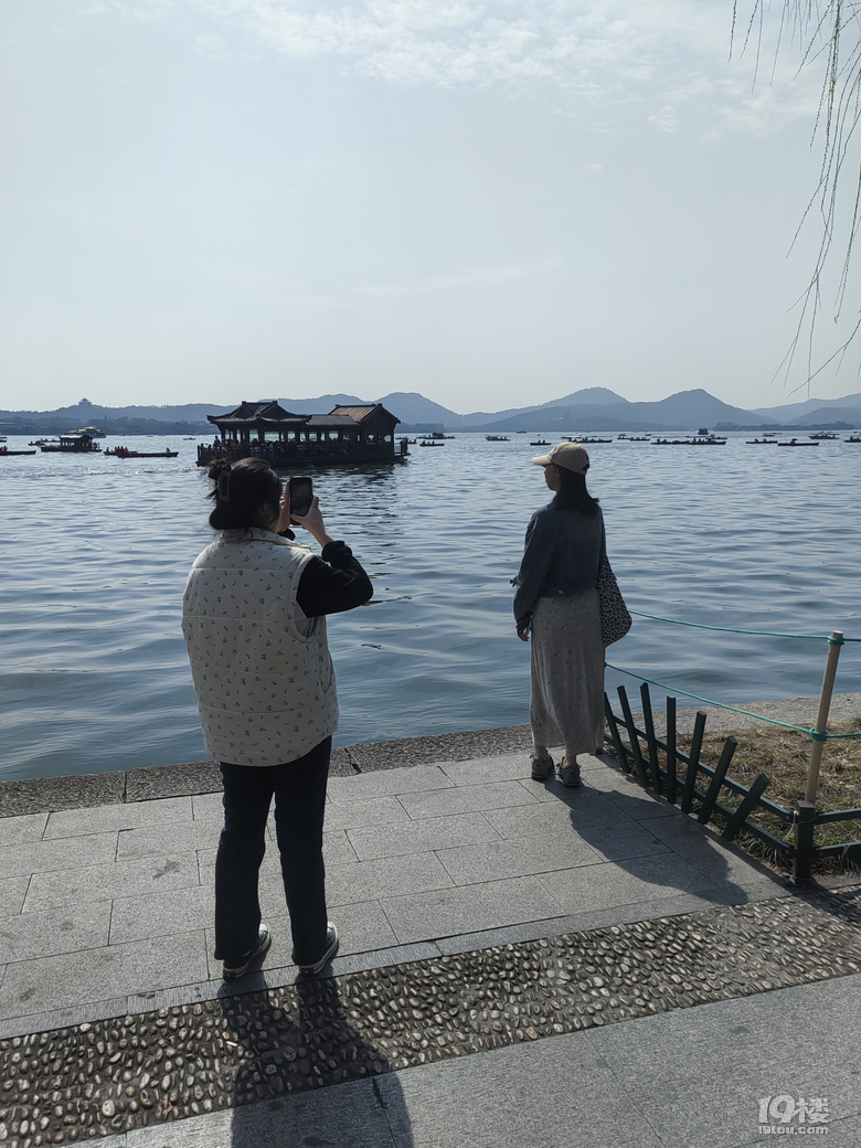 今天天氣太熱了，許多游客脫掉冬裝，穿上夏裝、短袖游西湖.