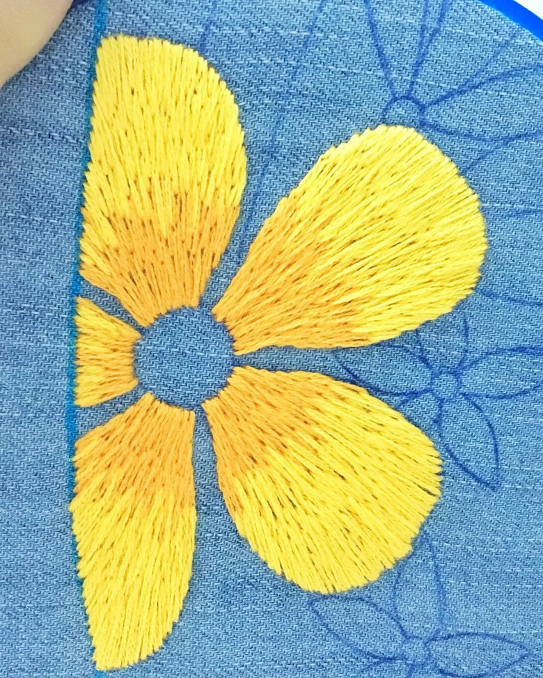 使用"裂线绣"的针法,在每个花瓣上,用橘红色的线