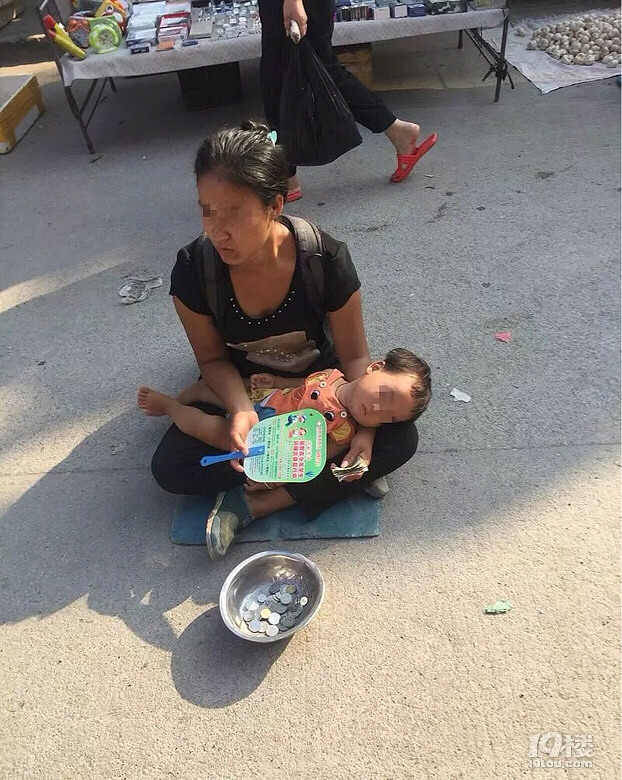 大溪菜市场一女人抱着孩子坐路中间乞讨有阴凉处不呆